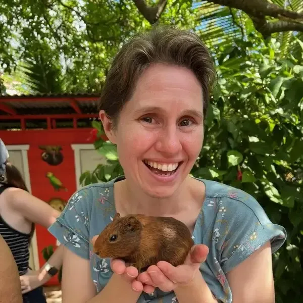 Sally Vernon smiling and holding a guinea pig.